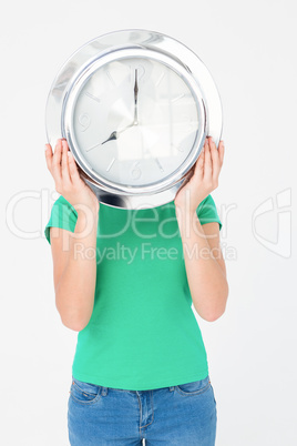 Brunette holding wall clock and hiding her face