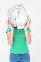Brunette holding wall clock and hiding her face