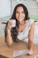 Pretty brunette reading newspaper with a mug