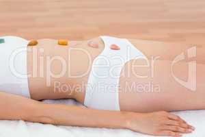 Relaxed brunette lying on mat with stones