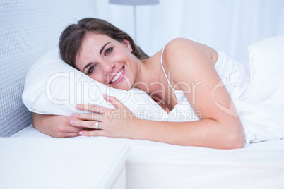 Happy woman smiling at camera in her bed