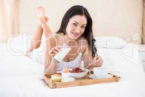 Pretty brunette eating her breakfast on bed