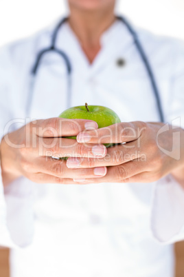 Confident female doctor holding green apple