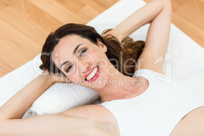 Smiling brunette lying on mat