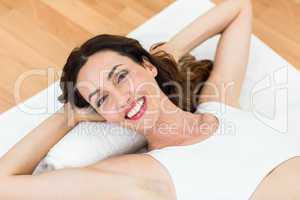 Smiling brunette lying on mat