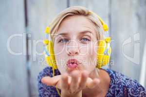 Pretty blonde woman listening music and blowing kiss