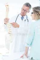 Doctor having conversation with his patient and showing spine mo