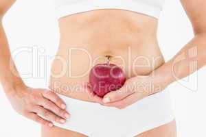 Fit woman holding an apple in front of her belly