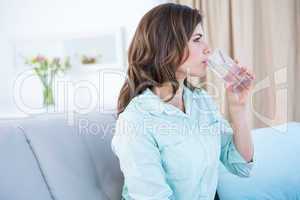 Thoughtful woman drinking a glass of water