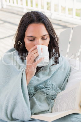 Pretty brunette sitting on a chair and drinking coffee
