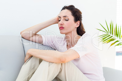 Sad brunette sitting on the couch