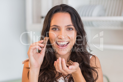 Happy pretty brunette eating chocolate