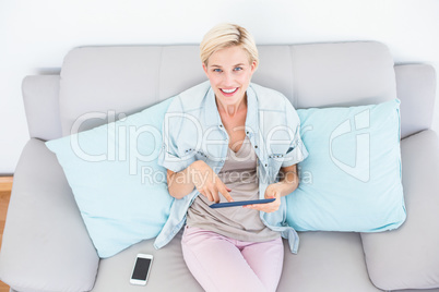 Pretty blonde woman using her tablet on the couch