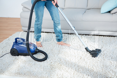 Woman using vacuum cleaner on carpet