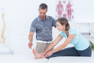 Physiotherapist helping his patient stretching