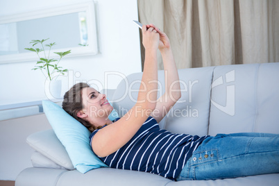 Pretty woman lying on couch taking a selfie