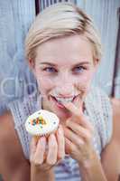 Pretty blonde woman tasting the cupcake