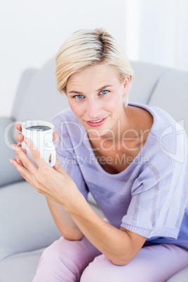 Pretty blonde woman relaxing on the couch and holding a mug