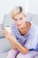 Pretty blonde woman relaxing on the couch and holding a mug