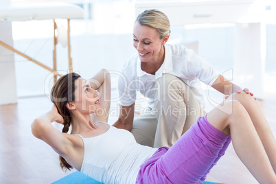 Trainer working with woman on exercise mat