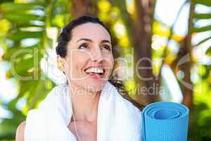 Fit beautiful brunette listening music and holding exercise mat