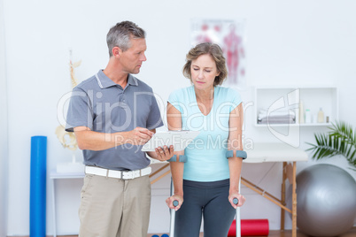 Woman using crutch and talking with her doctor