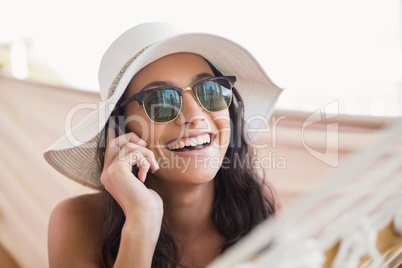 Pretty brunette relaxing on a hammock and calling with her mobil
