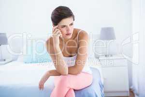 Thoughtful woman sitting on her bed