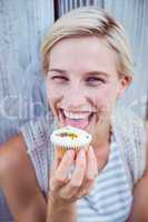 Pretty blonde woman tasting the cupcake