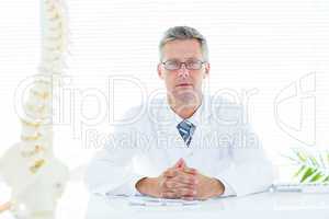 Doctor sitting at his desk looking at camera