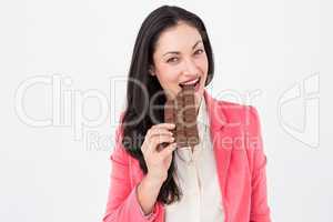 Smiling brunette biting bar of chocolate