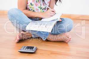 Pretty brunette writing and calculating on the floor