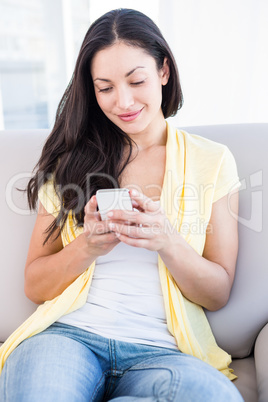 Pretty brunette using smartphone on couch