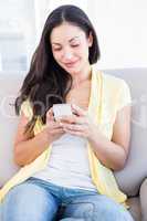 Pretty brunette using smartphone on couch