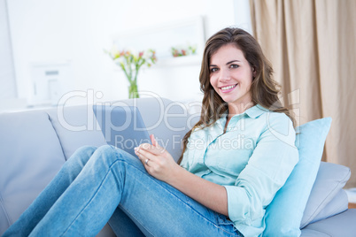 Happy brunette using her tablet pc on couch