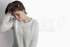Sad pretty brunette leaning against wall
