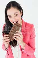 Smiling brunette biting bar of chocolate