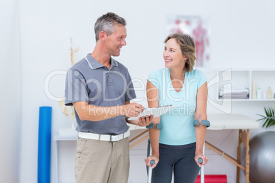 Woman using crutch and talking with her doctor