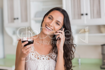 Pretty brunette on the phone having glass of wine