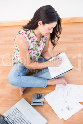 Pretty brunette writing on a paper while calculating