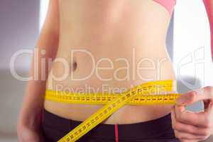 Slim woman measuring waist with tape measure