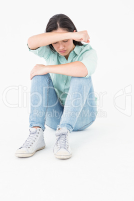 Sad woman sitting on the floor and hiding her face