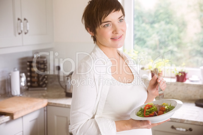 Pregnant woman having bowl of salad