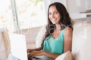 Pretty brunette using her laptop on the couch