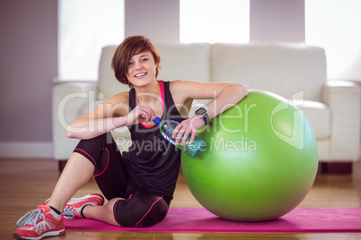 Fit woman sitting next to exercise ball