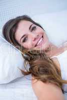 Happy woman in bed smiling at camera