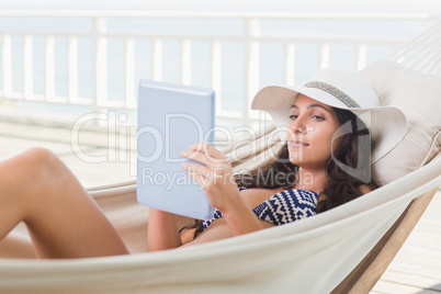 Pretty brunette relaxing on a hammock and using tablet pc