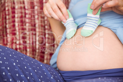 Pregnant woman holding baby shoes over bump