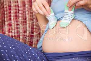 Pregnant woman holding baby shoes over bump