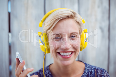 Pretty blonde woman listening music with her mobile phone